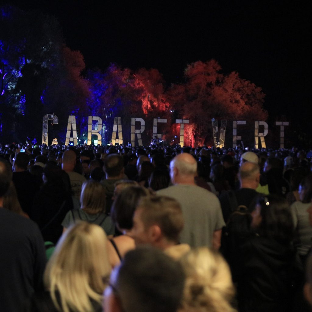 Foule de festival de nuit. A l'arrière plan le mot Cabaret Vert illuminé.